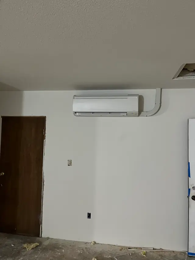 A new ductless head on a white wall in a room still being finished