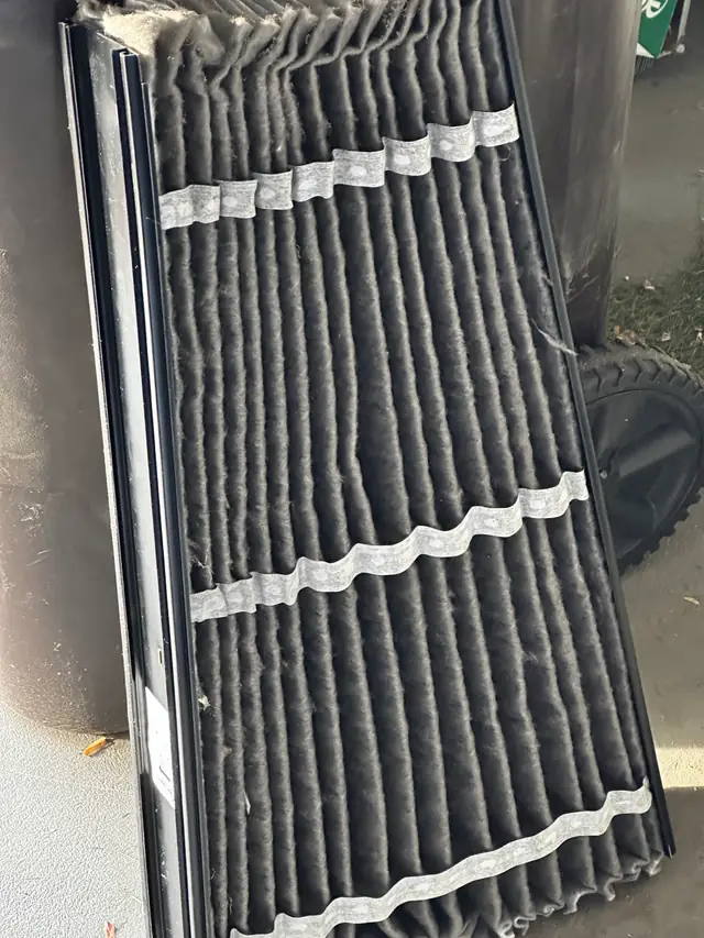 A pleated air filter grey with dust, pulled on a maintenance visit