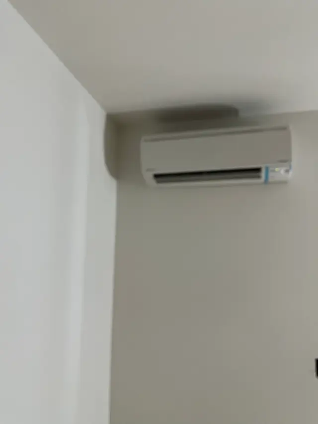 A white wall-mounted ductless head installed high in the corner of a finished white room